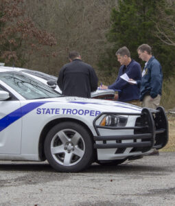 Three Arkansas State Troopers are gathered around their patrol car while participating in a CART exercise
